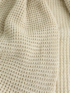 Macro detail of cream waffle knit texture showing 3D honeycomb weave of the long cardigan