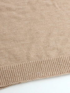 Detailed macro shot of camel knit sweater texture showing high-quality ribbed hem
