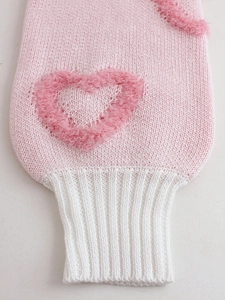 Women's pink knit sweater with white ribbed cuffs and a soft plush heart patch on sleeve