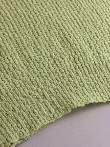 Detalle del suéter verde pistacho que muestra la textura del punto y el dobladillo