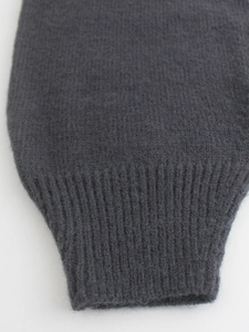 Close-up of charcoal grey knit sweater showing ribbed cuffs and soft wool texture