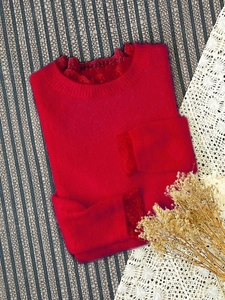Détail du pull en maille rouge avec dentelle au col et texture douce et moelleuse