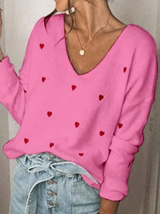 Dettaglio del maglione rosa con scollo a V e motivi a cuore rosso per donne in autunno