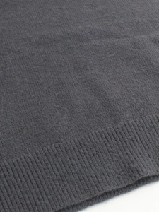 Detail shot of the ribbed hem and soft charcoal knit fabric on this cozy turtleneck sweater