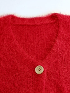 Detail of red fuzzy knit cardigan featuring a V-neckline and cream-colored button