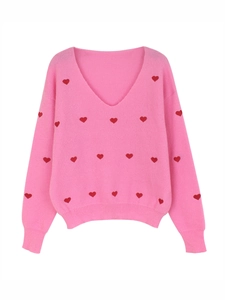 Dettaglio del maglione in maglia rosa con scollo a V a coste e ricami a cuore rossi