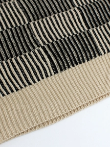 Detailed close-up of geometric knit pattern and ribbed hem of the bicolor sweater