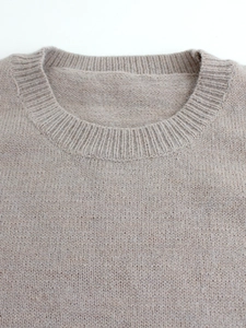 Close-up of oatmeal knit sweater showing ribbed crewneck and soft fabric texture