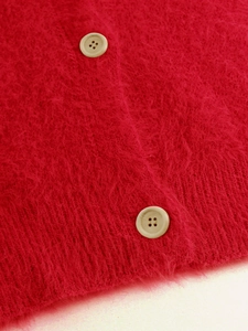 Close-up of fluffy red knit cardigan showing soft mohair texture and cream buttons