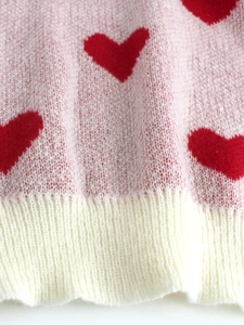 Detail of pink knitted sweater showing red heart pattern and soft mohair texture