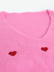 Dettaglio maglione rosa in maglia con scollo a V e ricamo a cuore rosso