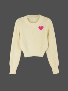Detail of soft cream knit sweater featuring a pink heart embroidery on the chest