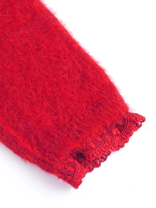 Détail de la manche d'un pull rouge avec dentelle délicate et texture moelleuse