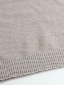 Detailed macro view showing the soft ribbed hem and fine knit texture of the beige sweater
