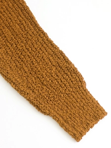 Primer plano del suéter de punto color caramelo con textura gruesa y detalle de dobladillo