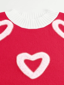 Detailed close-up of white heart embroidery on red knitted sweater fabric