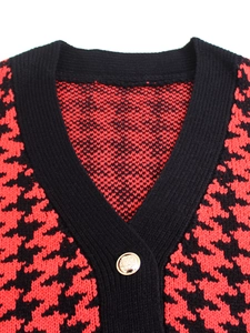 Primo piano dettagliato di un gilet in maglia pied de poule rosso con bottone dorato