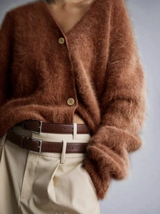 Detailed macro view of the fuzzy brown mohair knit texture and button on the cardigan