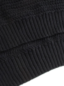 Close-up of black knitted sweater fabric showing ribbing and herringbone stitch patterns