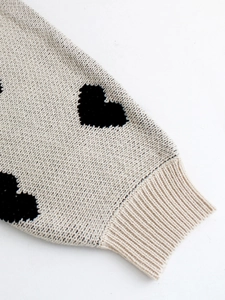 Manica di cardigan in maglia beige con motivi a cuore neri e dettaglio polsini