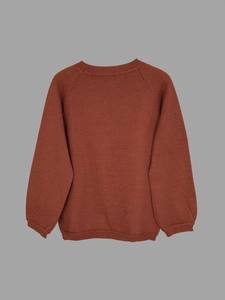 Close-up of terracotta raglan sleeve knit sweater with ribbed cuffs and hem details