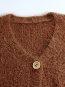 Close-up detail of fluffy V-neck knit cardigan with cream resin button and plush texture
