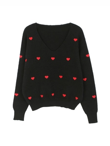 Dettaglio dello scollo a V a coste e dei motivi a cuore rosso sul maglione in maglia nera
