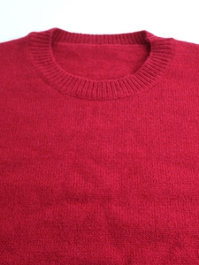 Close-up of the classic crew neck and fine ribbed knitting texture on a red sweater