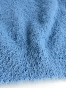 Detailed close-up of fluffy light blue plush knit fabric with soft textured faux fur fibers