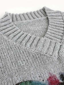 Detailed view of the ribbed V-neckline and chunky knit texture of a grey sweater