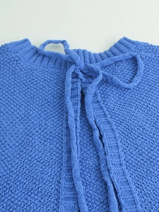 Detailed close-up of blue chunky knit neckline with stylish bow tie decoration