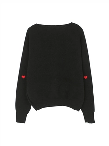 Dettaglio del ricamo a cuore rosso sul gomito di un maglione nero in maglia a coste