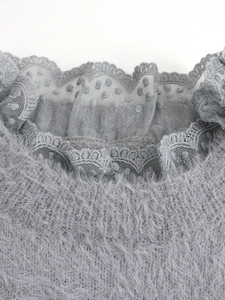 Détail du pull en maille grise avec texture pelucheuse et col orné de dentelle délicate