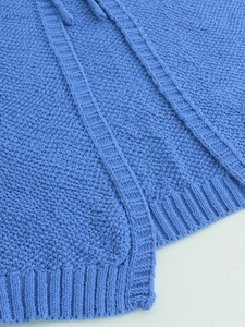 Detail of royal blue knitted top showing ribbed hem and textured knit fabric