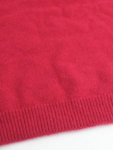 Macro shot of soft red knitted fabric texture and ribbed cuff detail on sleeve
