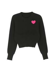 Detail of pink embroidered heart patch on a black long sleeve crew neck knit sweater