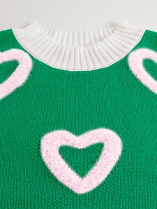 Detail of green knit sweater with pink plush heart and white ribbed round neckline