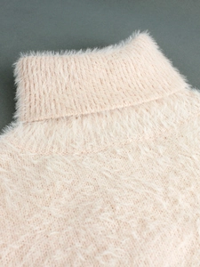 Close-up of pink fuzzy knit sweater featuring a thick turtleneck and soft plush texture