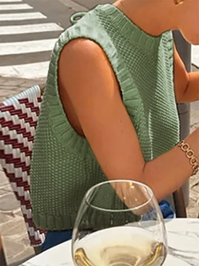 Close-up of grass green knitted sleeveless vest featuring ribbed edges and round neck