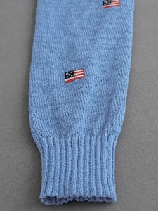 Close-up of light blue knit sweater cuff with ribbed edge and American flag embroidery