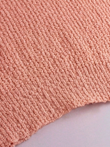 Detalle de tejido de punto coral con textura de relieve y dobladillo acanalado