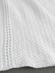 Gros plan sur un tissu en maille blanche avec texture ajourée et détails de maille douce