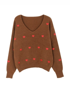 Dettaglio della trama a maglia del maglione con scollo a V e motivi a cuori rossi
