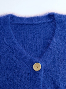 Detail of soft Klein blue mohair knit cardigan featuring a V-neck and stylish resin button