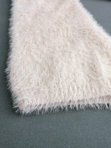 Close-up of soft fluffy knit sweater texture in light pink with detailed ribbed cuff