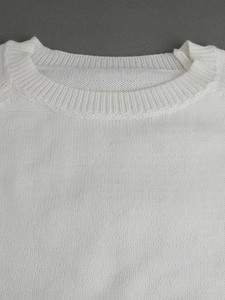 Close-up of the ribbed crewneck design and fine knit texture on a white long sleeve sweater