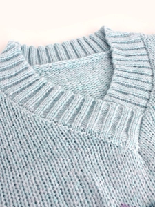 Close-up of the light blue knitted sweater showing the ribbed round neckline and texture