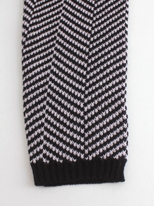 Detail der Strickware mit schwarz-weißem Fischgrätenmuster und geripptem Bündchen