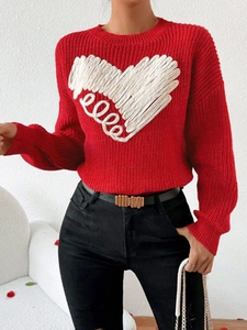 Detail of red knit sweater featuring a 3D white embroidered heart with spiral design