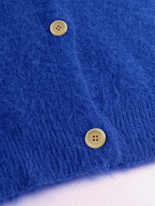 Close-up of blue fluffy knit cardigan with soft plush texture and beige buttons